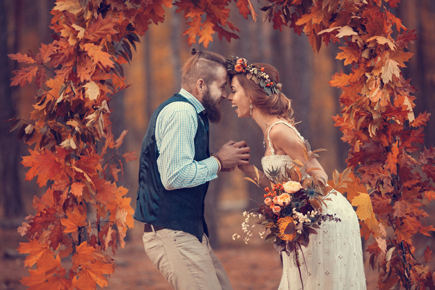 Beautiful-bridal-couple-bearded-bride-and-groom-in-wreath-laughing-happily-in-autumn-oak-leaf-arch