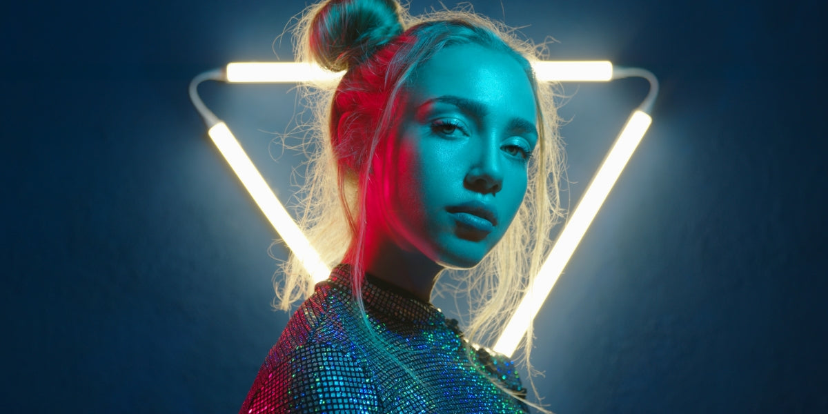 Young woman looking at the camera in the neon light of the club. Camera zoom. Portrait of a beautiful futuristic girl close-up. Lady in multicolor glow.